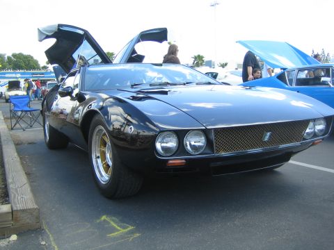 1968 Ford Mustang - This black sports car features distinctive gullwing doors and gold-accented wheels, seen at an outdoor car show.