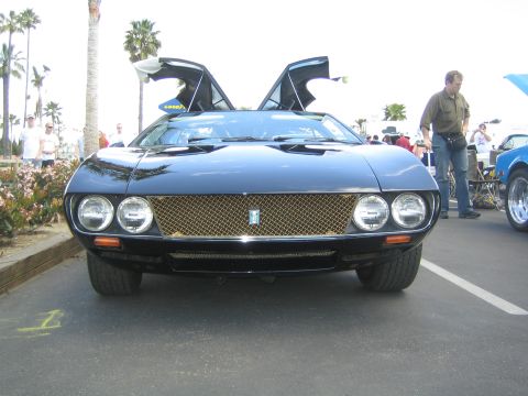1968 Ford Mustang - A black sports car with gullwing doors is parked at an outdoor car show.