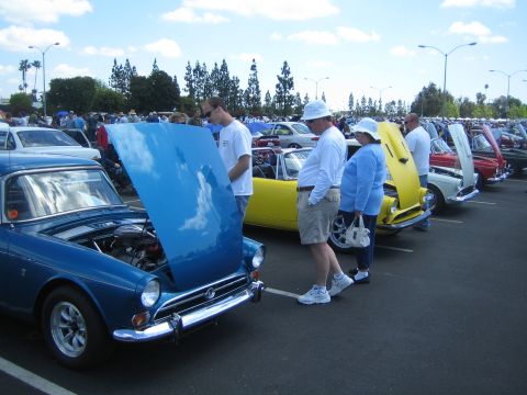 1968 Ford Mustang - A car show displays multiple vehicles with their hoods open under a cloudy sky.