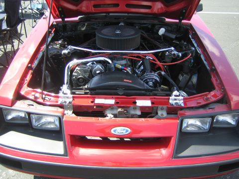 1968 Ford Mustang - The engine bay of a red Ford Mustang, showing the motor and various components.