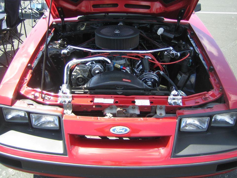 Red Ford Mustang engine bay with chrome accents and aftermarket air filter