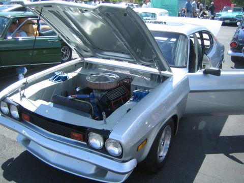 1968 Ford Mustang - Silver coupe with engine exposed at a car show, with other vehicles in the background.