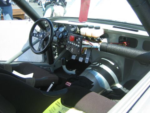 1968 Ford Mustang - The interior of a modified vehicle shows a roll cage, racing wheel, and a complex dashboard with multiple gauges and switches.