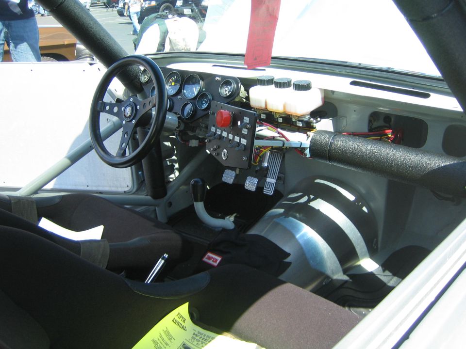 Racing car interior with roll cage, racing wheel, and custom dashboard with gauges and switches