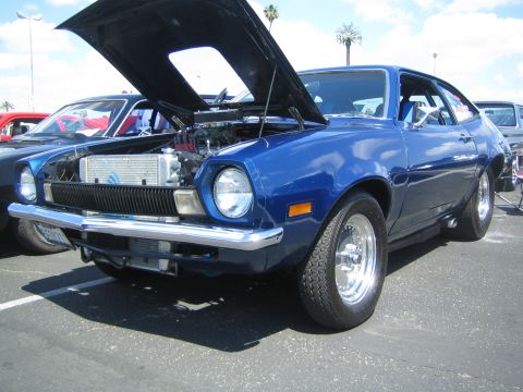 1968 Ford Mustang - A blue 1974 Ford Pinto coupe is displayed with its hood open, revealing the engine and radiator.