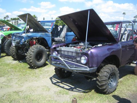 1968 Ford Mustang - Multiple off-road vehicles, including a purple one with its hood open, are lined up at an outdoor event.