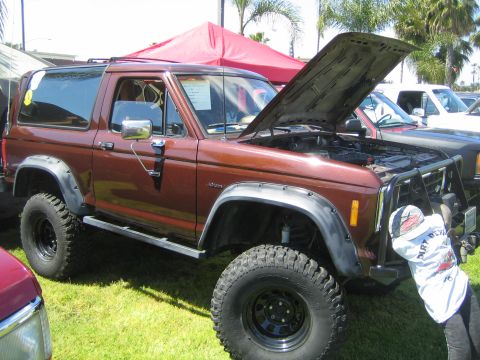 1968 Ford Mustang - A brown Ford Bronco II is displayed with its hood open at a car show.