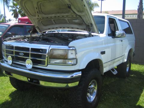 1968 Ford Mustang - A white Ford Bronco is parked on the grass with its hood open, revealing the engine compartment.