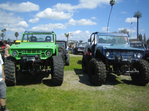 1968 Ford Mustang - Two heavily modified Ford Broncos are displayed outdoors, their off-road capabilities under a partly cloudy sky.