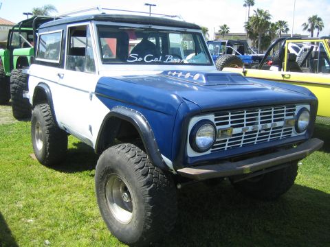 1968 Ford Mustang - A modified Ford Bronco is parked on grass with other vehicles in the background.