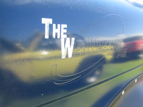 1968 Ford Mustang - A dark blue vehicle displays text and graphics on its side, with reflections of other vehicles visible.