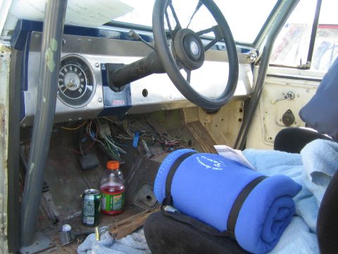 1968 Ford Mustang - The interior of a 1968 Ford Bronco shows its roll cage and exposed wiring, with a blue blanket on the seat.
