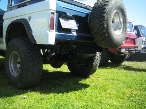 1968 Ford Mustang - A white and blue Ford Bronco is parked on grass next to other vehicles, with a spare tire mounted on the rear.