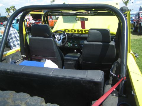 1968 Ford Mustang - Interior view of a yellow Jeep Bronco, black seats, a roll cage, and "BRONCO" lettering on the dashboard.