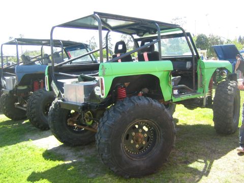 1968 Ford Mustang - Modified off-road vehicles with custom roll cages and suspension systems are lined up on a grassy area.