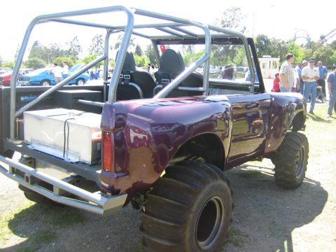 1968 Ford Mustang - A heavily modified vehicle with oversized tires and a roll cage is parked outdoors at an event.