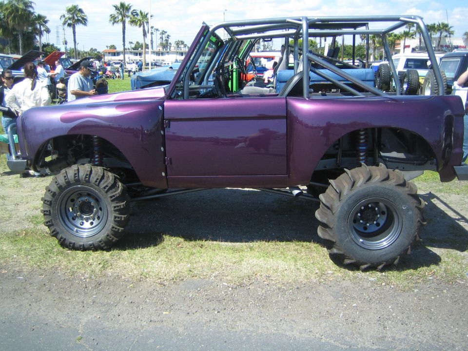 Purple custom off-road vehicle with roll cage and large tires, side view