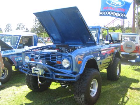 1968 Ford Mustang - A blue Ford Bronco is displayed with its hood open, parked on grass next to another vehicle.