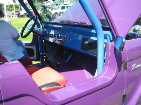 1968 Ford Mustang - Customized 1968 Ford Bronco interior features a blue roll cage and unique seat upholstery. Other vehicles are parked nearby.