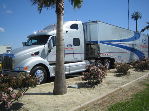 1968 Ford Mustang - Silver semi-truck and trailer with Ford Racing livery parked outdoors under a clear blue sky.