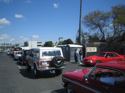 1968 Ford Mustang - A line of vehicles, including a Ford Bronco, are parked under a sunny sky with palm trees.