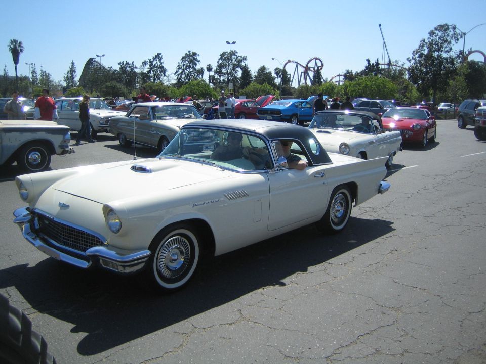 White 1957 Ford Thunderbird with black hardtop, side view. "Thunderbird" script visible on fender