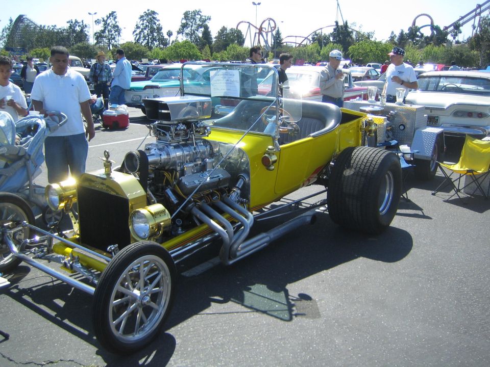 Yellow hot rod with a large supercharger and exposed V8 engine, viewed from a 3/4 front angle