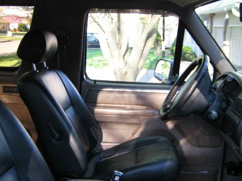 1995 Ford Bronco - View from the passenger seat shows the driver's side interior and a tree outside the window.