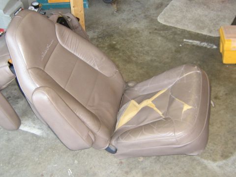 1995 Ford Bronco - Two tan leather car seats are shown, one of which has significant damage to its upholstery.