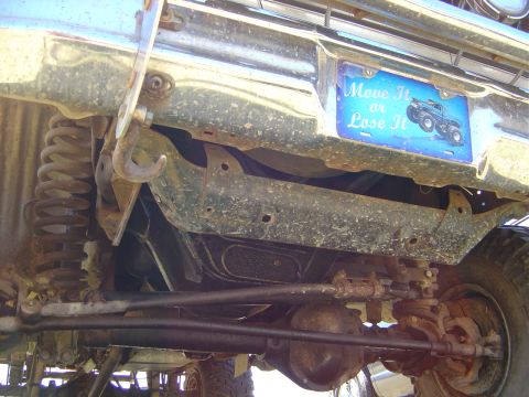 1986 Ford Bronco - The underside of a vehicle is visible, suspension and steering parts, along with a decorative license plate.