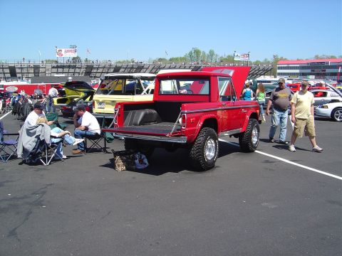 1986 Ford Bronco - A red 1978 Ford Bronco pickup truck is parked at an outdoor event with people and other vehicles around.