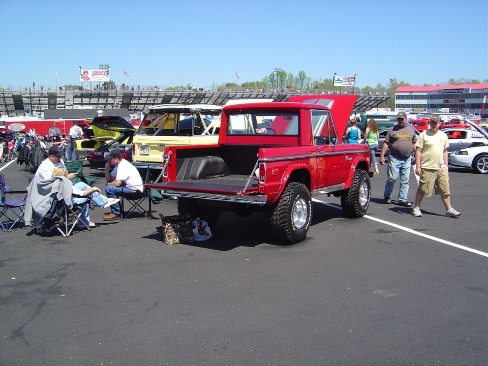 Red 1978 Ford Bronco pickup truck with tailgate down, lifted suspension, and aftermarket wheels