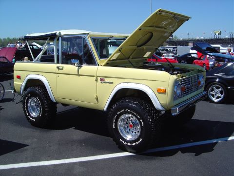 1986 Ford Bronco - A yellow Ford Bronco with its hood open is parked at an outdoor event.