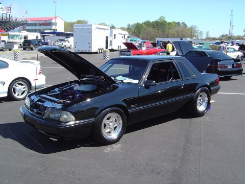 1986 Ford Bronco - A black coupe with its hood open at an outdoor event, with other vehicles and trailers in the background.