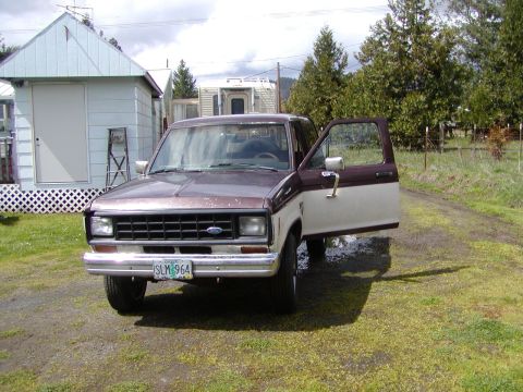 1987 Ford Bronco II - This two-tone Ford Ranger pickup truck is parked outside with its driver's door ajar.
