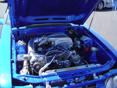 1986 Ford Bronco - Customized engine bay a prominent supercharger and polished components, all finished in a vibrant blue.
