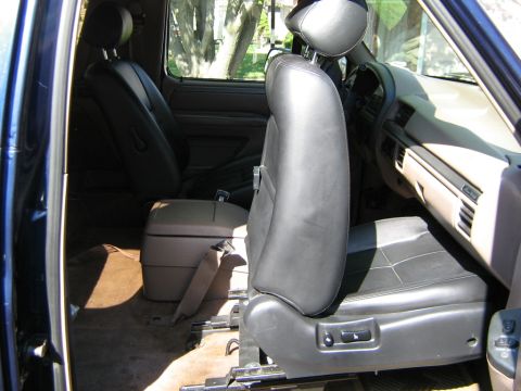 1995 Ford Bronco - The interior of a blue SUV is shown, leather seats and a center console.