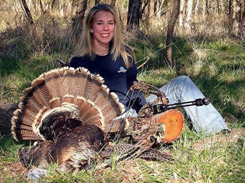 1986 Ford Bronco - A successful hunter poses with her prize turkey and bow in a wooded area.