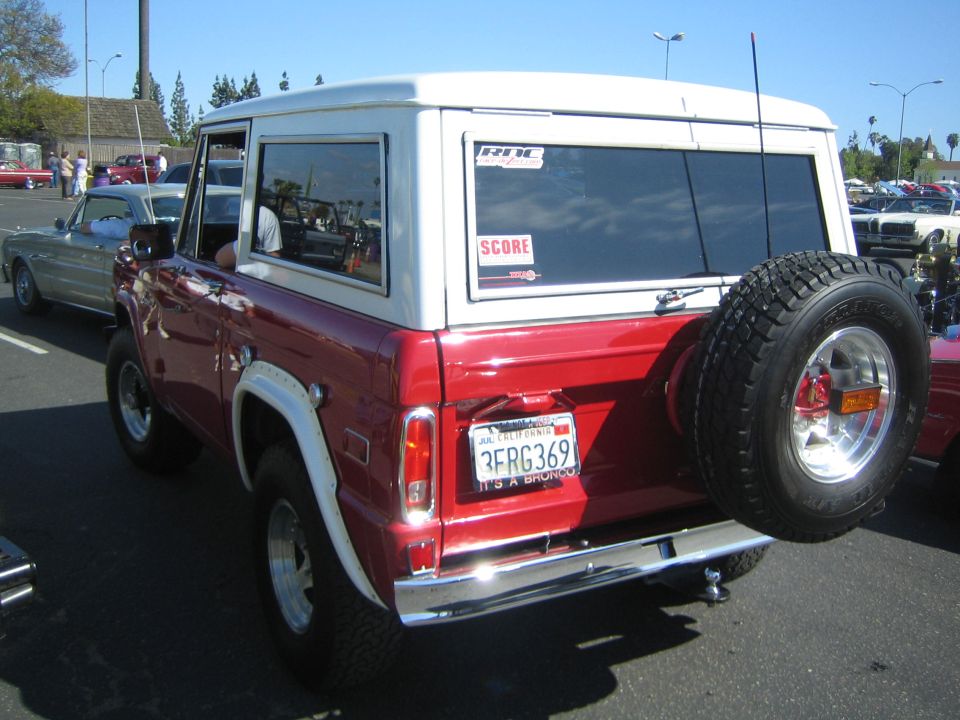 Red and white Ford Bronco with a spare tire mounted on the rear, seen from the back