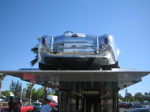1968 Ford Mustang - A highly polished, vintage-style sports car is displayed on a platform at an outdoor event.