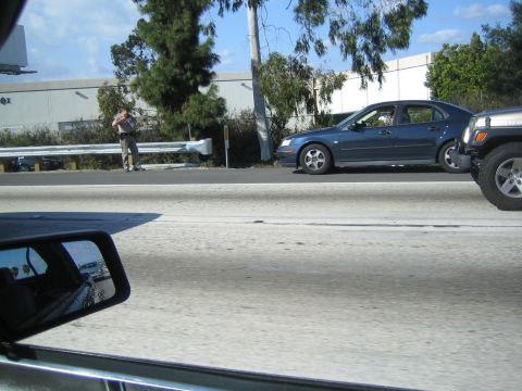 1968 Ford Mustang - A blue sedan and a jeep are seen on the highway next to a person standing by a guardrail.