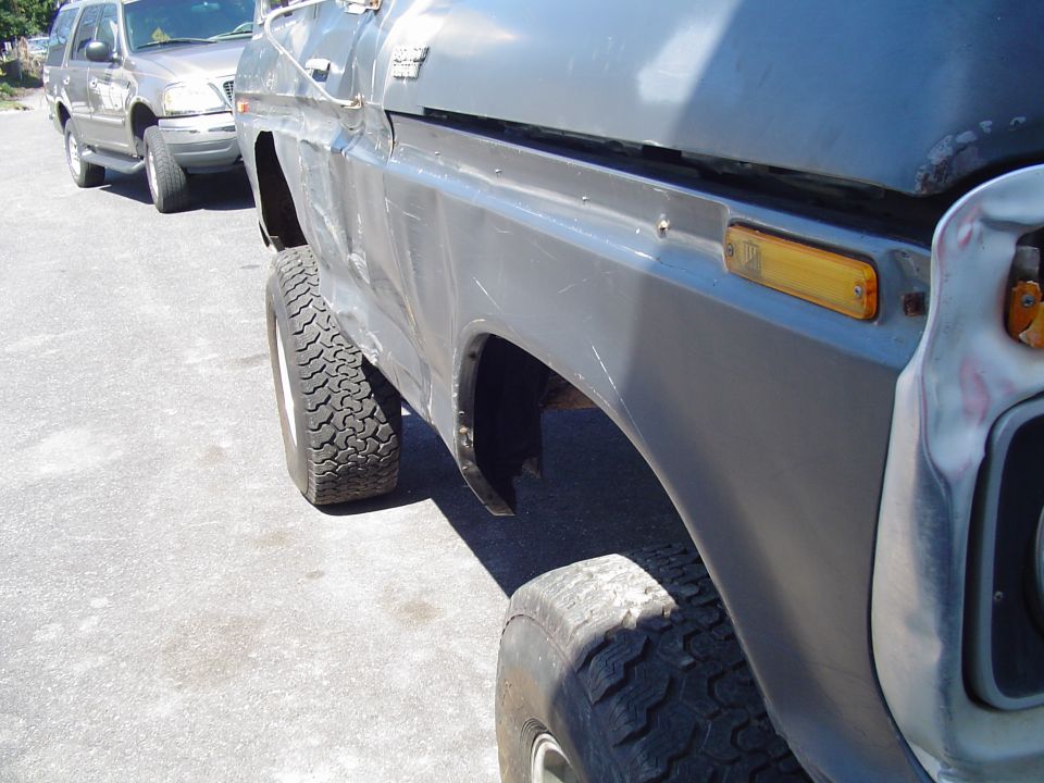 Side view of a 1979 Ford Bronco with aftermarket wheels and tires, parked behind another SUV