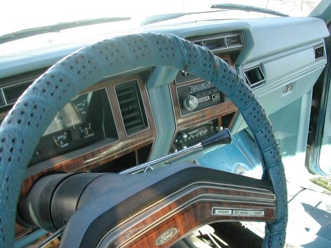1981 Ford Bronco - The interior of a 1981 Ford Bronco features a blue steering wheel cover and wood grain accents on the dashboard.