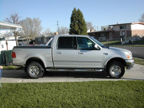 1981 Ford Bronco - This pickup truck has a crew cab and a long bed, parked in a suburban setting.