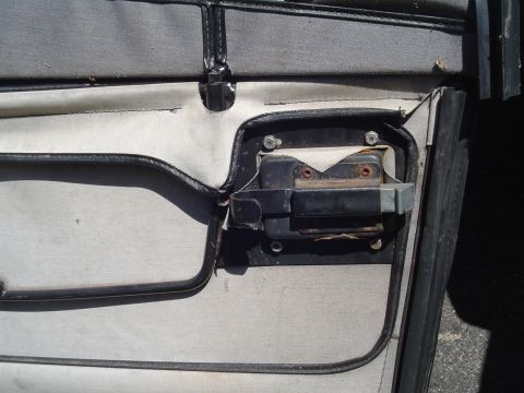 1989 Jeep YJ - The interior of a vehicle door shows the latch mechanism and surrounding trim panel.