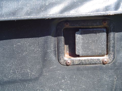 1989 Jeep YJ - Close-up of a dark gray textured door panel with a square metal handle, showing signs of wear.