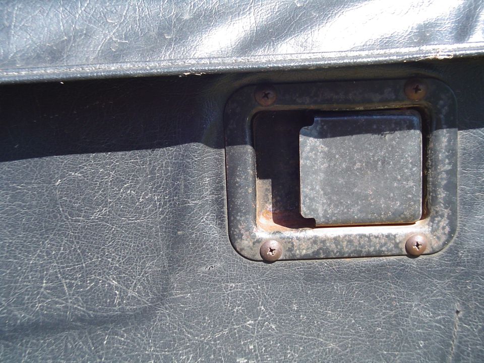 Dark gray textured door panel with a square metal handle and visible screws
