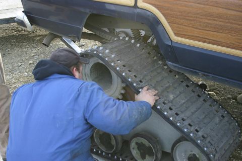 2003 Jeep TJ - A person is installing snow tracks onto a vehicle that has wood paneling on its side.