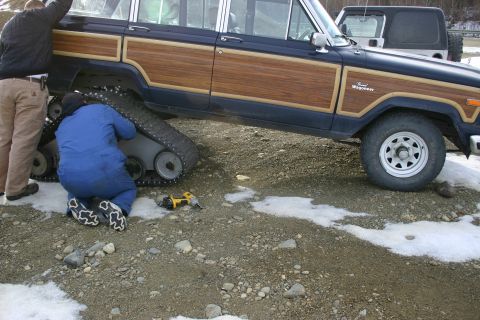 2003 Jeep TJ - A dark blue Jeep Wagoneer with wood paneling is being modified with tracks, with another Jeep visible in the background.