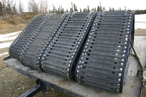 2003 Jeep TJ - A set of three black snowmobile tracks are loaded onto a trailer, ready for transport.